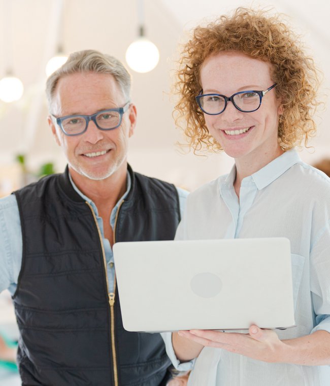 ein Mann und eine Frau im Büro mit einem Laptop in der Hand